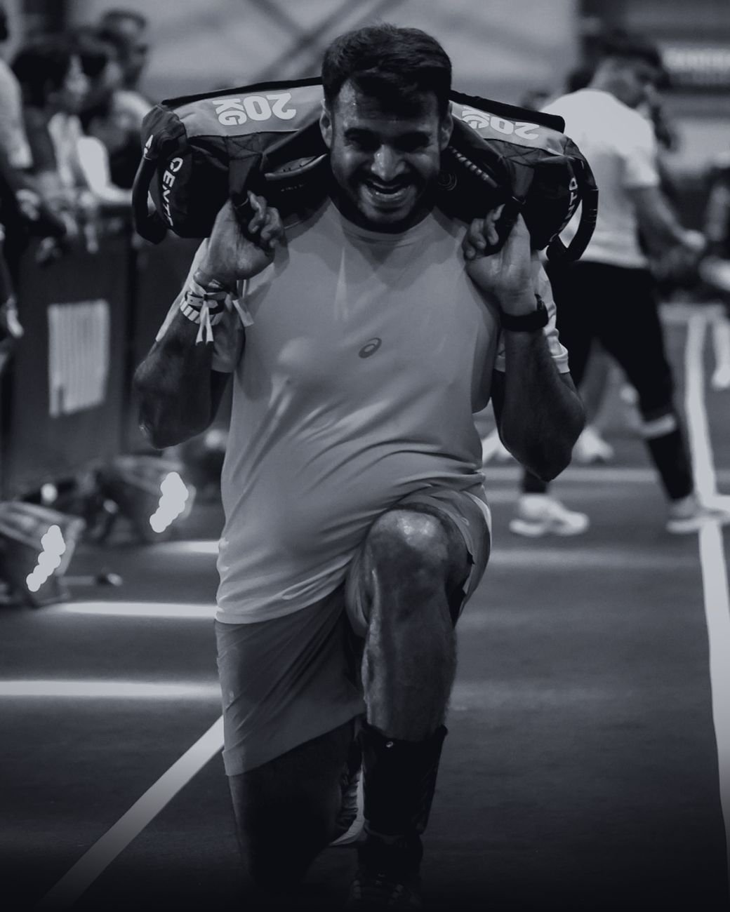 HYROX athlete smiling through the sandbag lunges